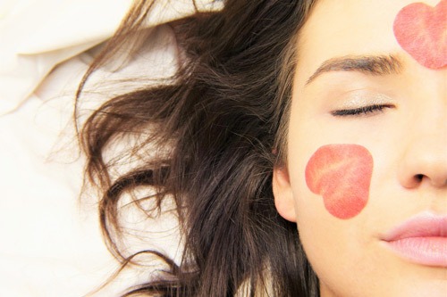 Girl with slices of strawberry on her cheek and forehead.