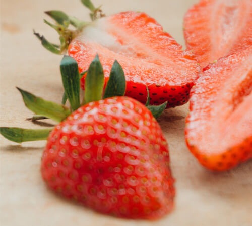 Two sliced strawberries on a table.